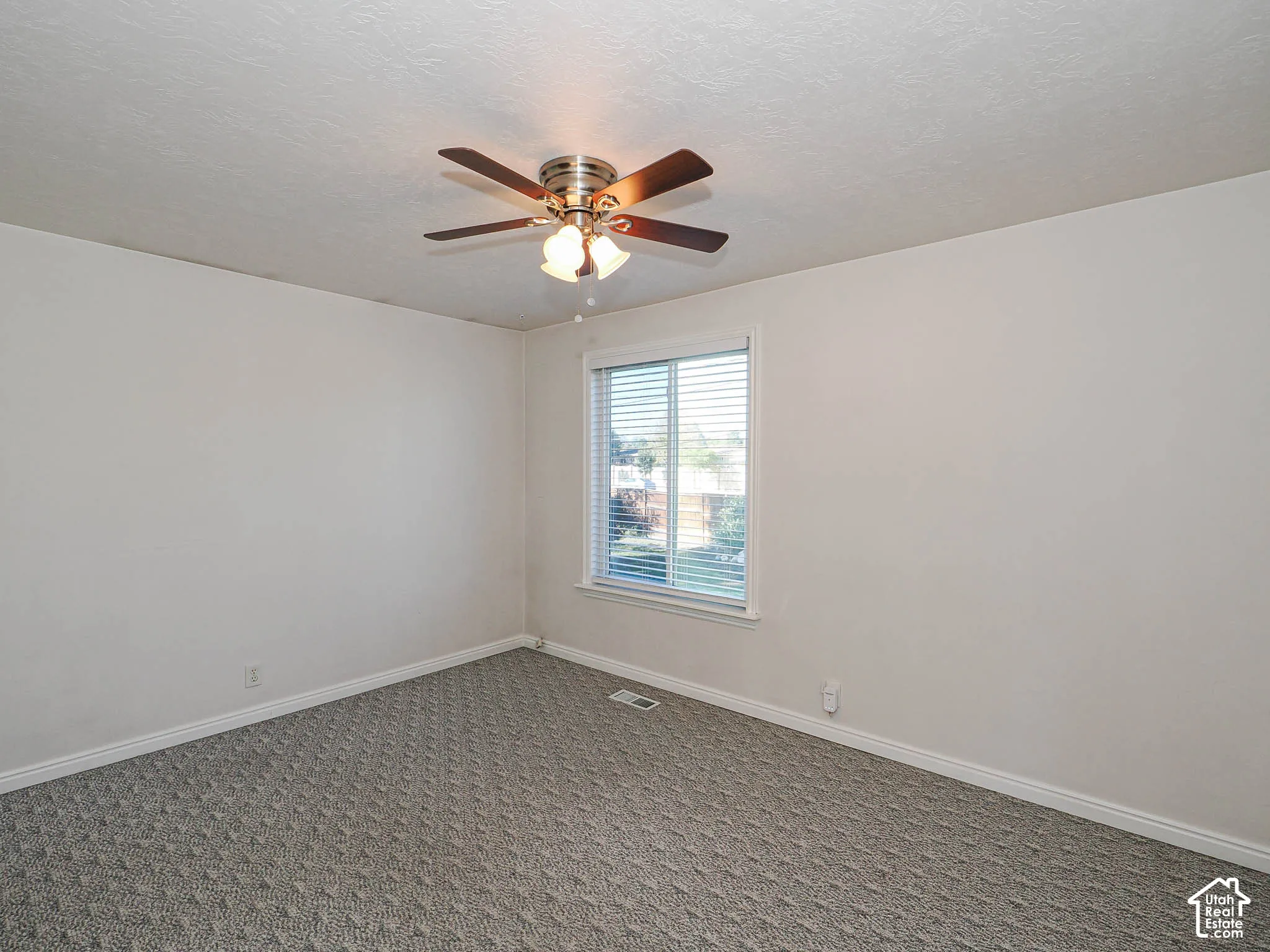 Wall-to-wall carpet flooring, ceiling fan with integrated lighting, window with horizontal blinds, and neutral wall tones
