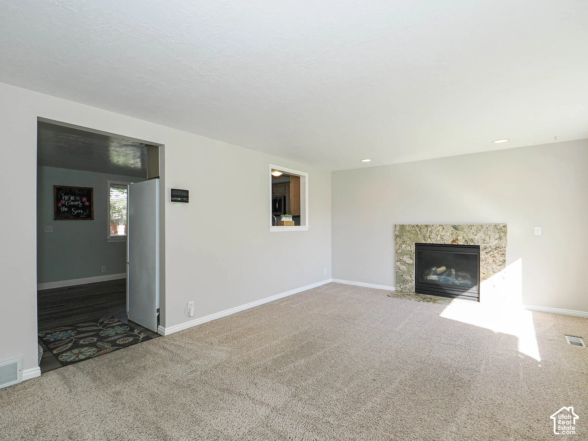 Carpeted living area featuring a fireplace with a stone surround