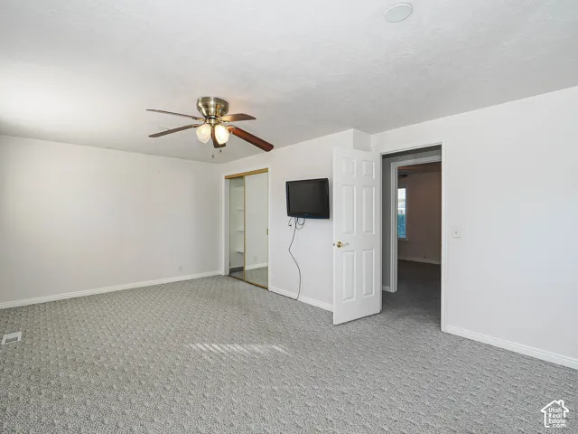 Ceiling fan with light fixture, carpeted flooring, white walls, white trim, mirrored closet doors