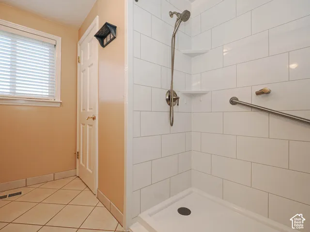 Shower with subway tile surround, integrated shelving, and a handheld shower fixture