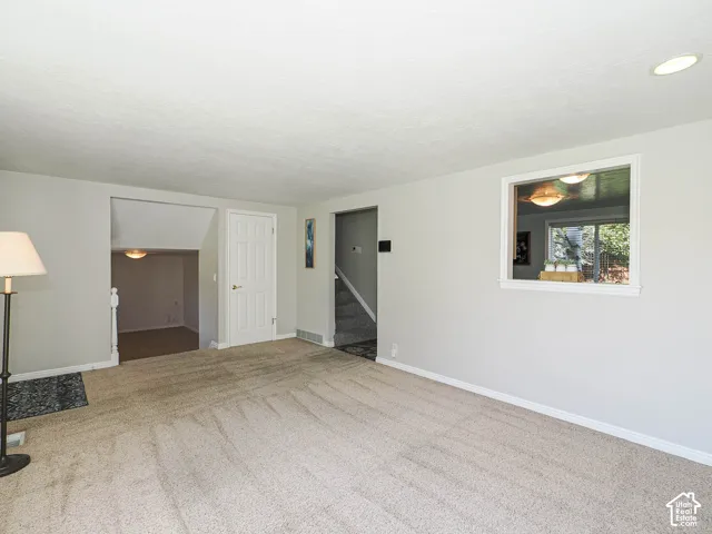Recessed lighting and a white trim window complement the light-colored walls and carpeted flooring