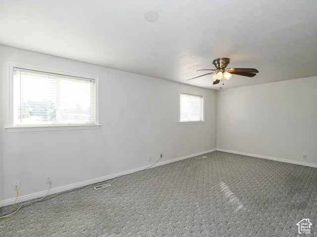 Recessed ceiling lighting, ceiling fan with integrated light fixture, two windows with blinds, and neutral carpeting