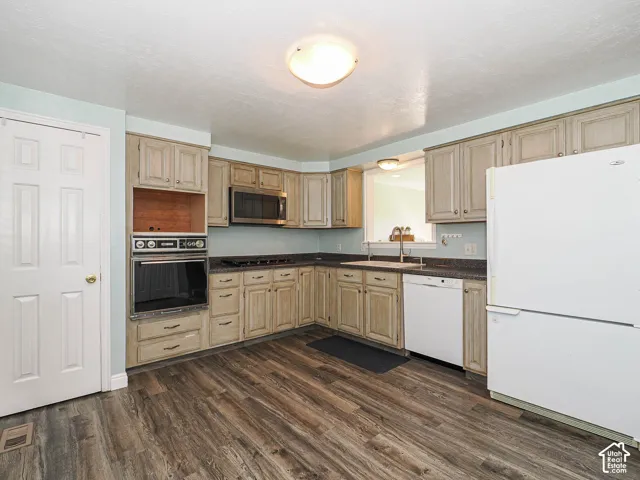Kitchen featuring wood-finish flooring, built-in wall oven, built-in microwave, and ample cabinetry