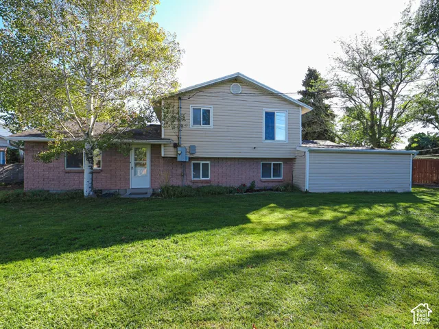 Expansive green lawn with mature trees and a two-story residence featuring brick and siding exterior finishes
