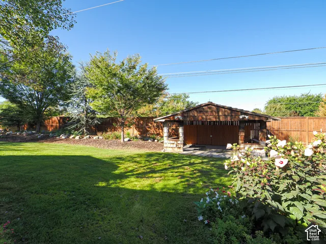 Expansive grassy yard with mature trees and a wood-slat privacy fence