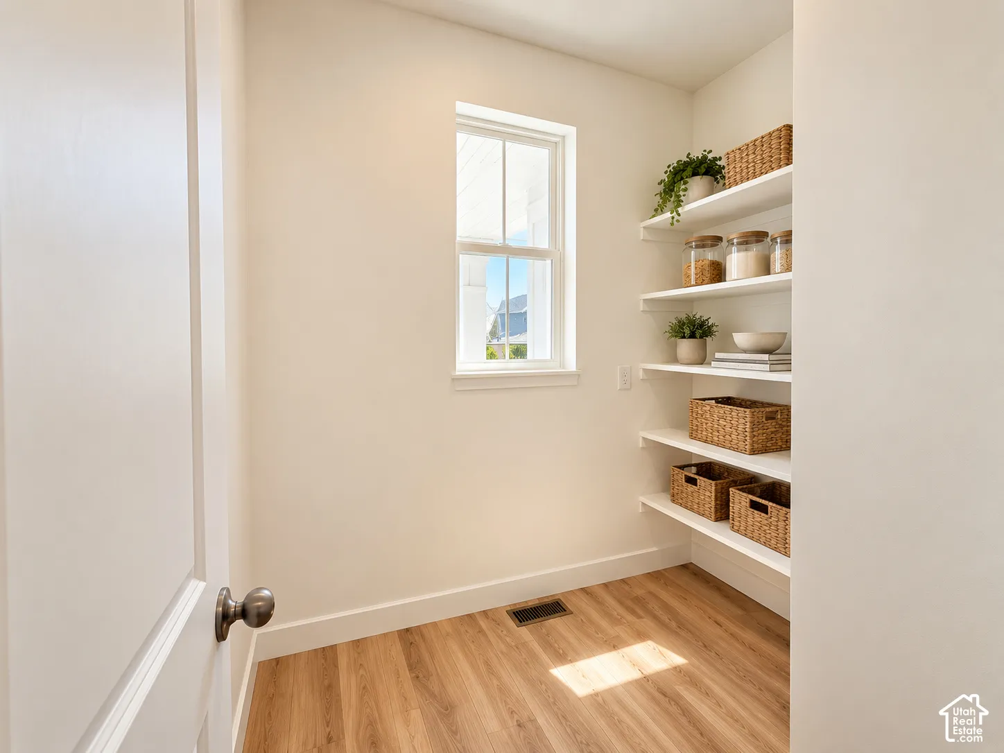 Windowed pantry featuring wood-finish flooring and ample built-in shelving