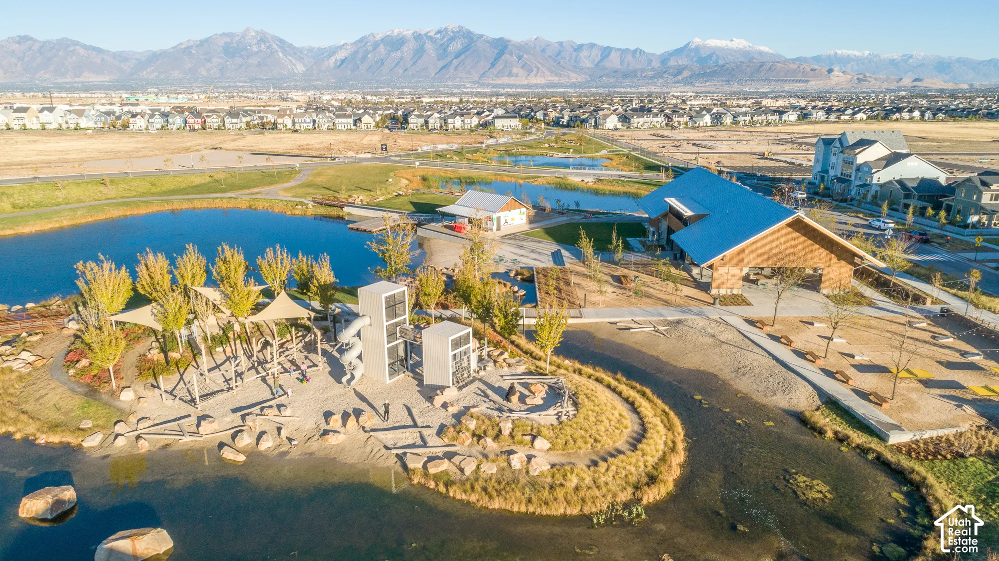 Expansive community grounds featuring a large pond, recreational play structures, and a substantial covered gathering pavilion