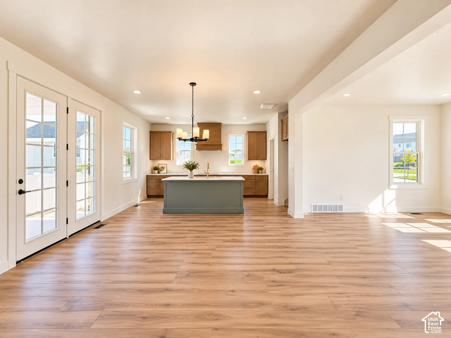 Spacious open-concept layout with wood-finish flooring, recessed lighting, and French doors
