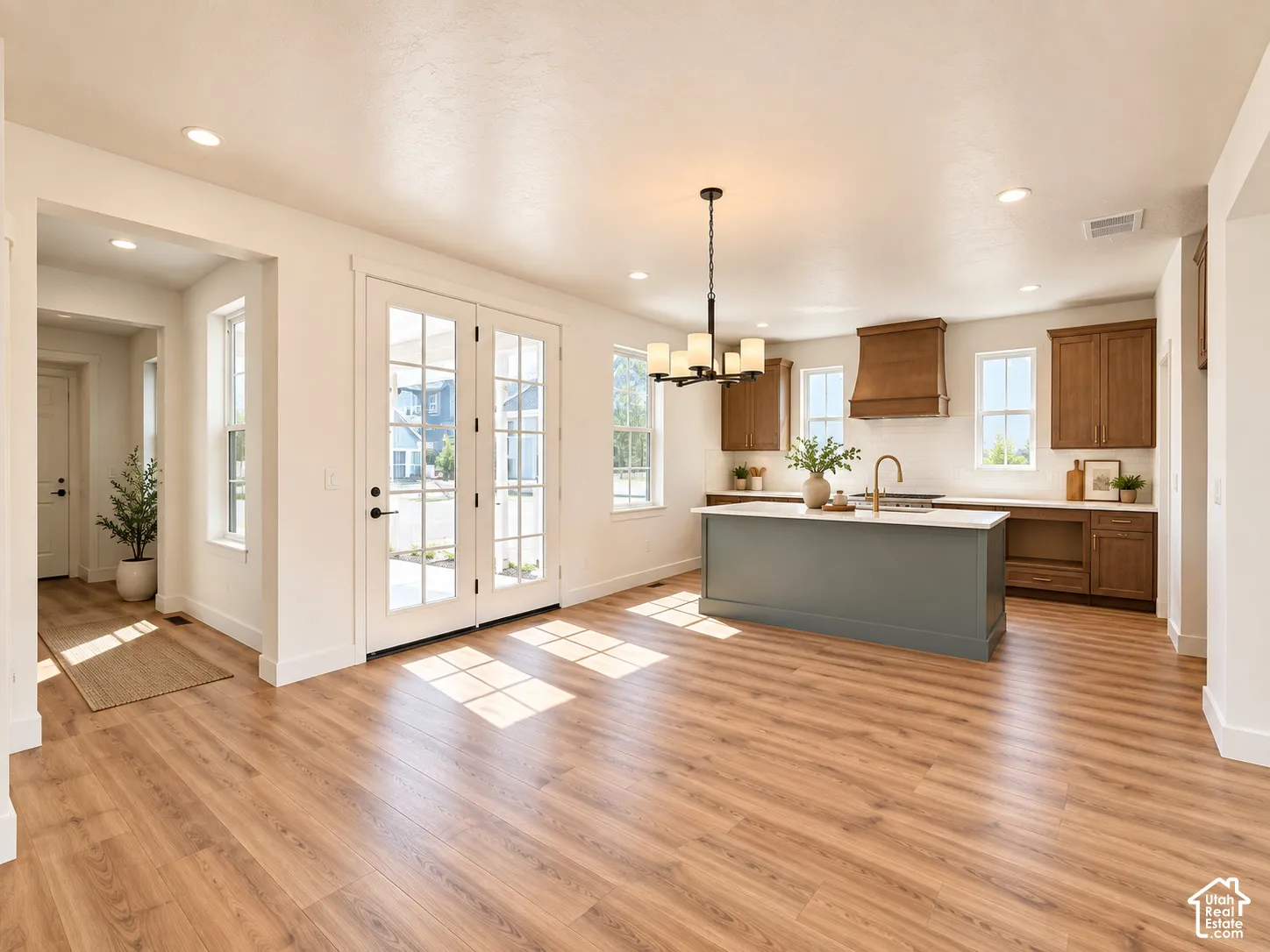 Open-concept kitchen with a gray island, wood cabinetry, and a gold-finish faucet