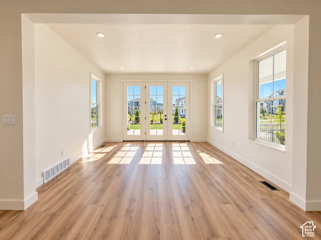 Wood-finish flooring, recessed ceiling lighting, multiple windows, and a set of French doors