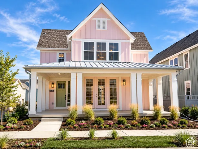 Inviting front porch with a metal roof, contrasting light green entry door, and pink french patio doors, framed by a landscaped garden bed
