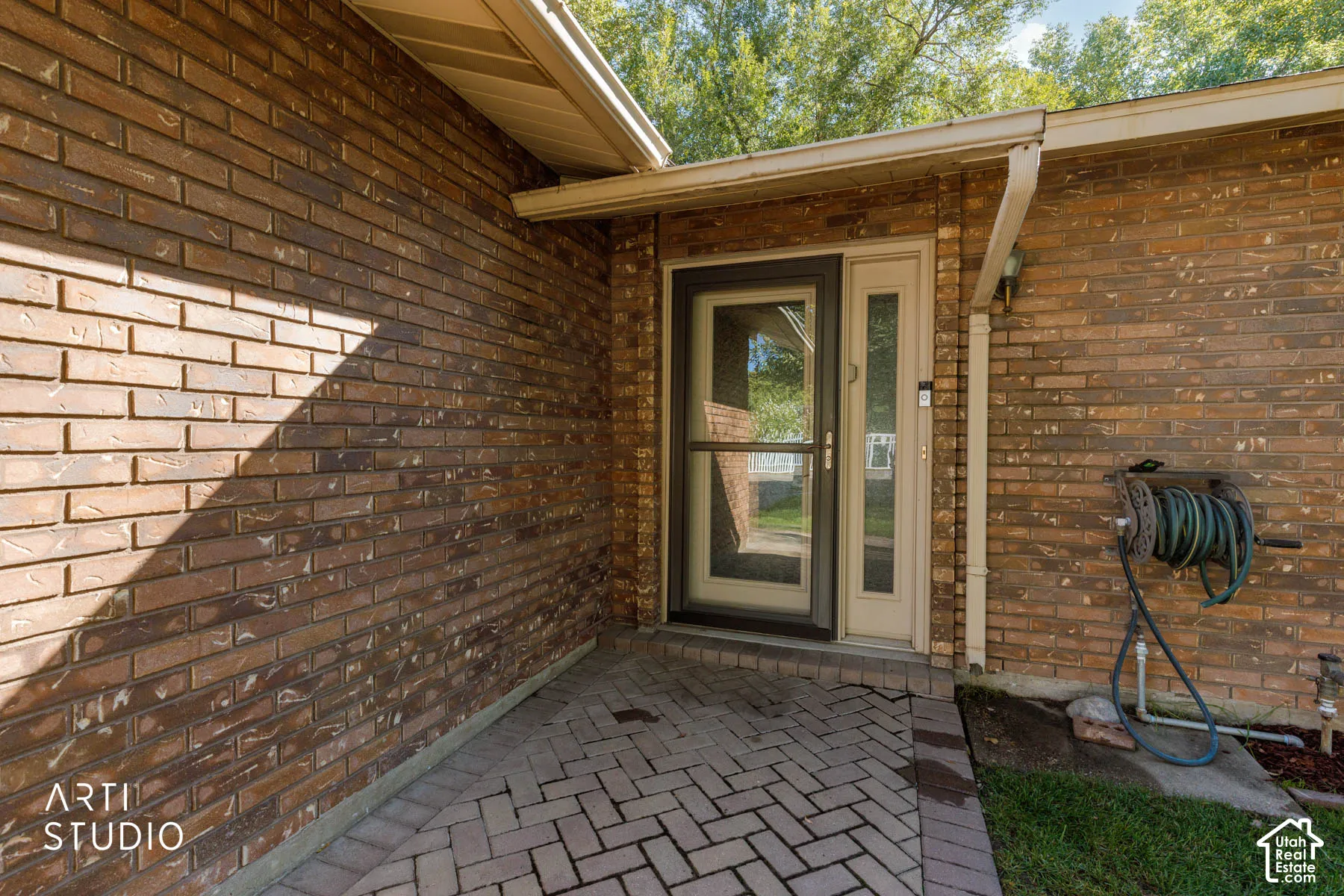 Brick exterior with a covered entry, glass storm door, and a light-colored main entry door