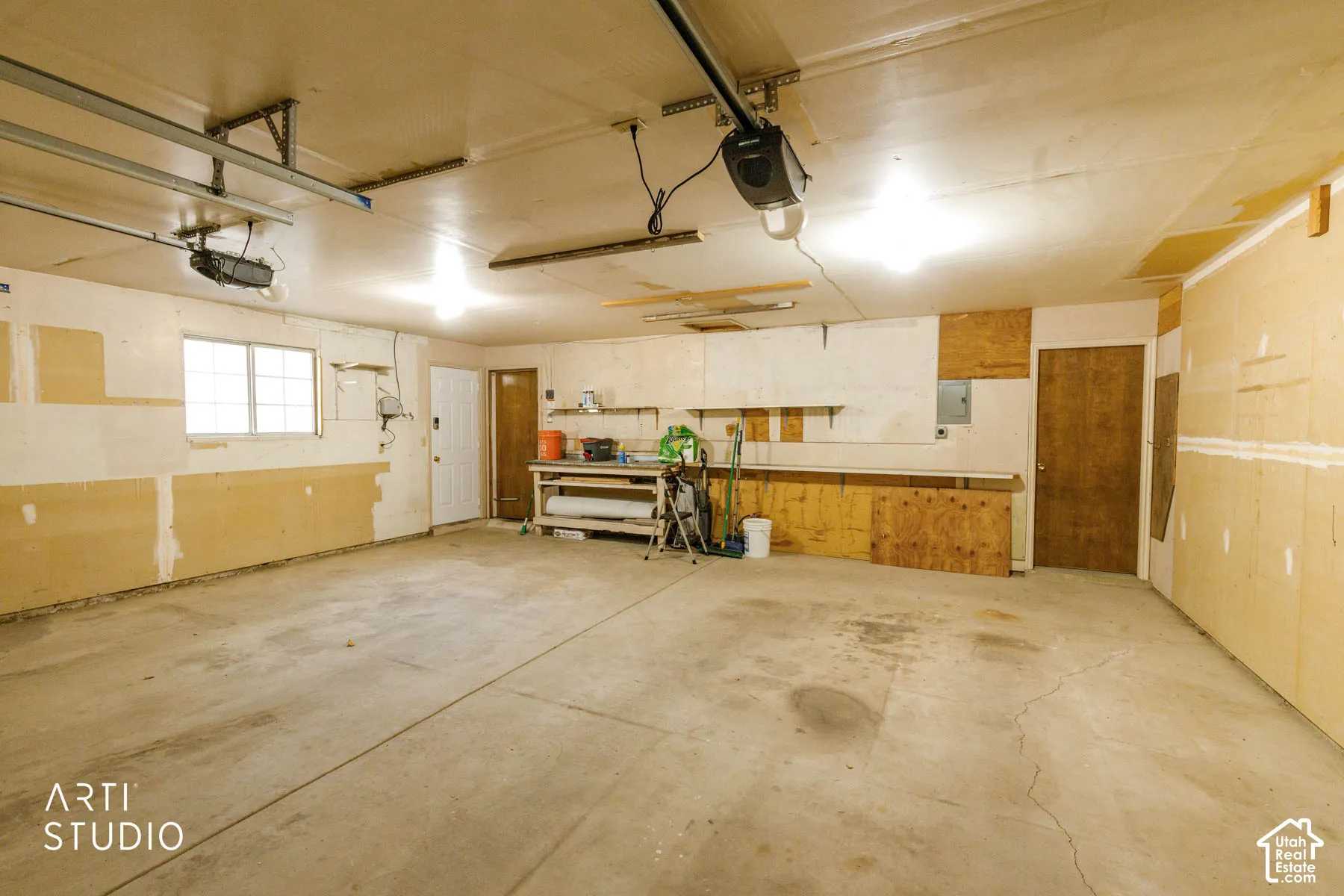 Attached garage with concrete flooring, fluorescent lighting, and a visible window