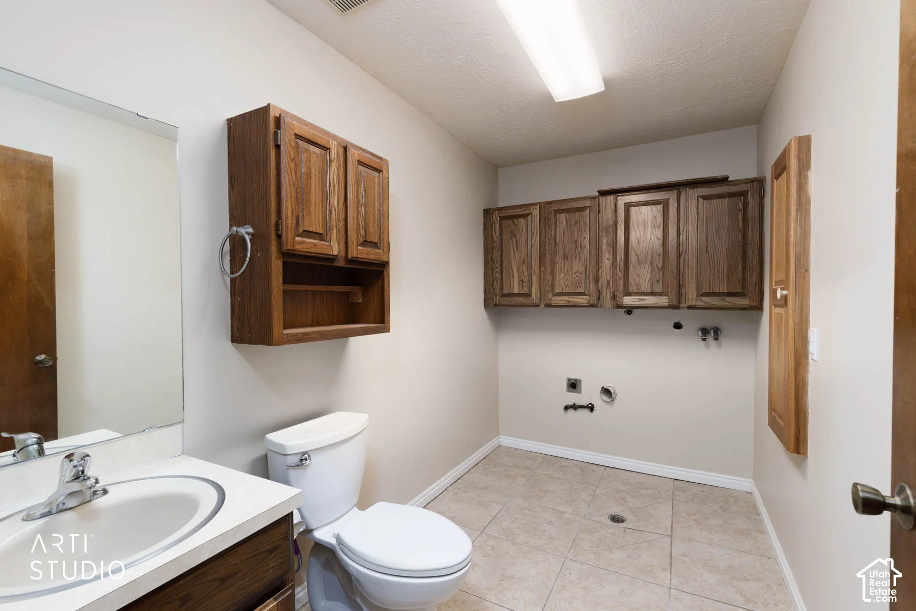 Laundry area with tiled flooring, white toilet, and built-in wood cabinetry