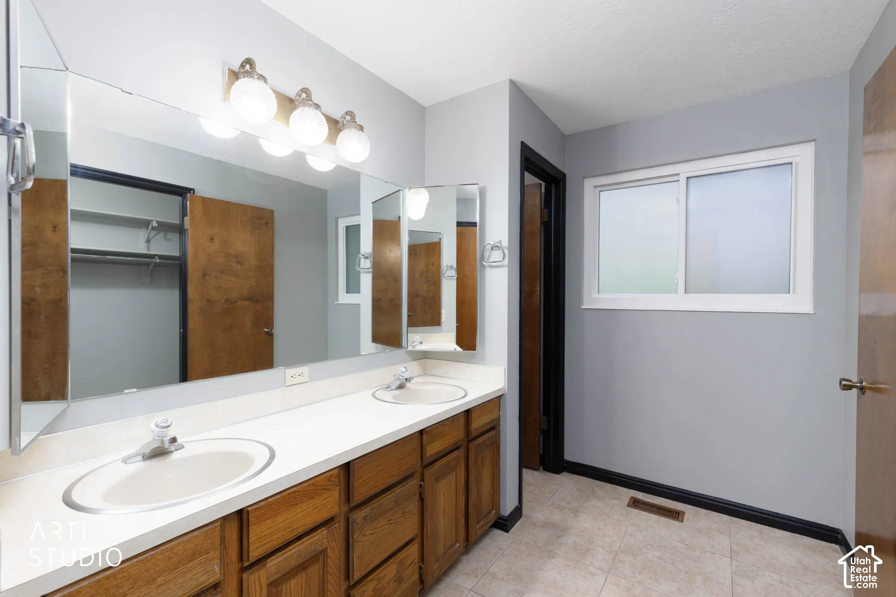 Dual vanity with integrated sinks, ample countertop space, wood-finish cabinetry, and a large wall-mounted mirror