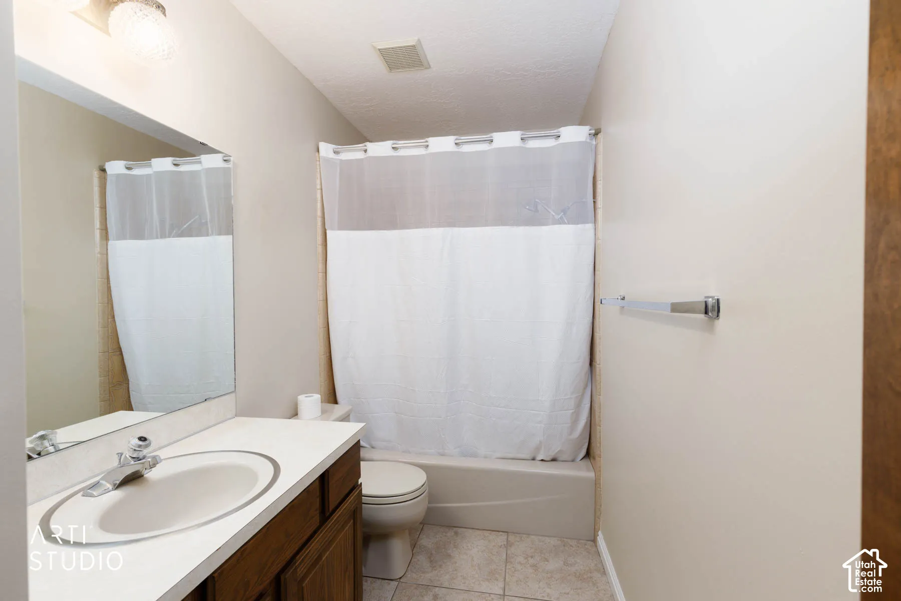 Bathroom featuring a built-in vanity with a countertop sink, a wall-mounted mirror, overhead lighting, a shower-tub combination, and tiled flooring