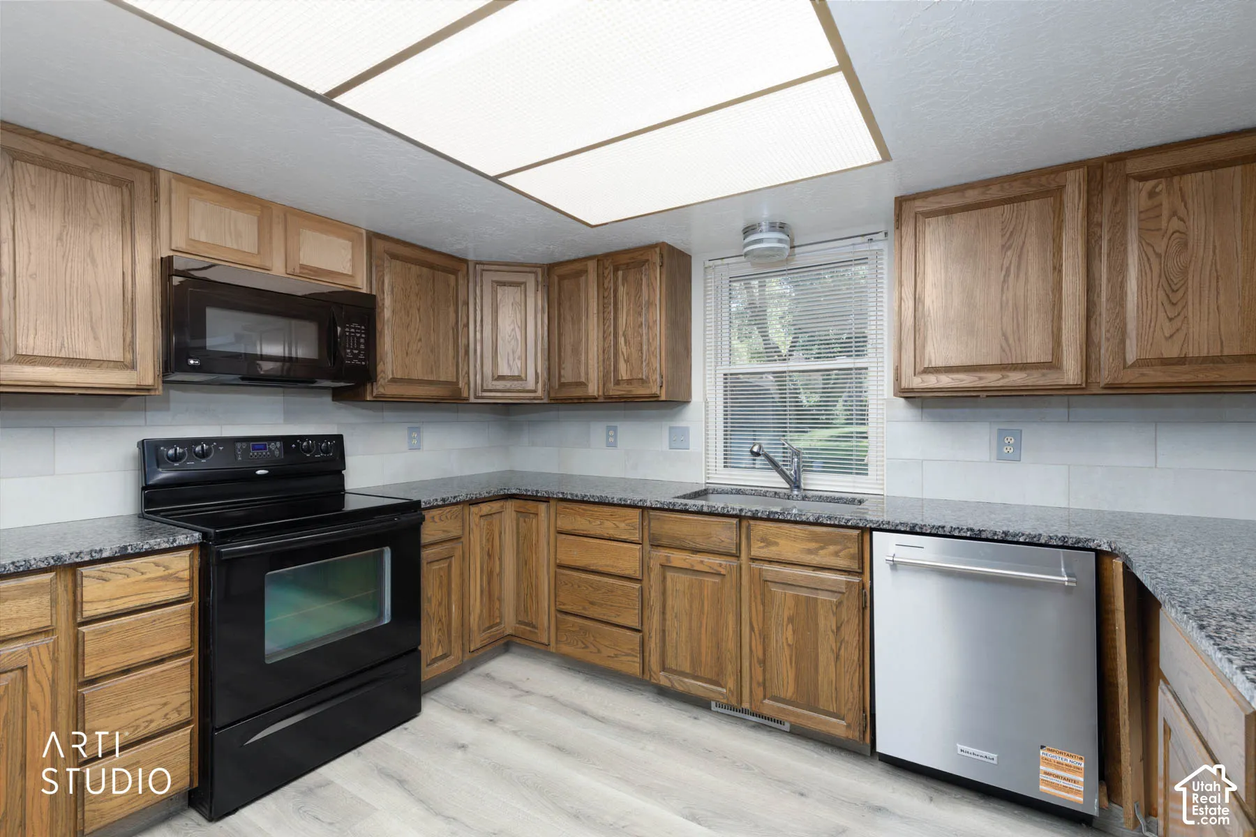 Kitchen featuring wood cabinetry, solid surface countertops, white subway tile backsplash, and wood-finish flooring