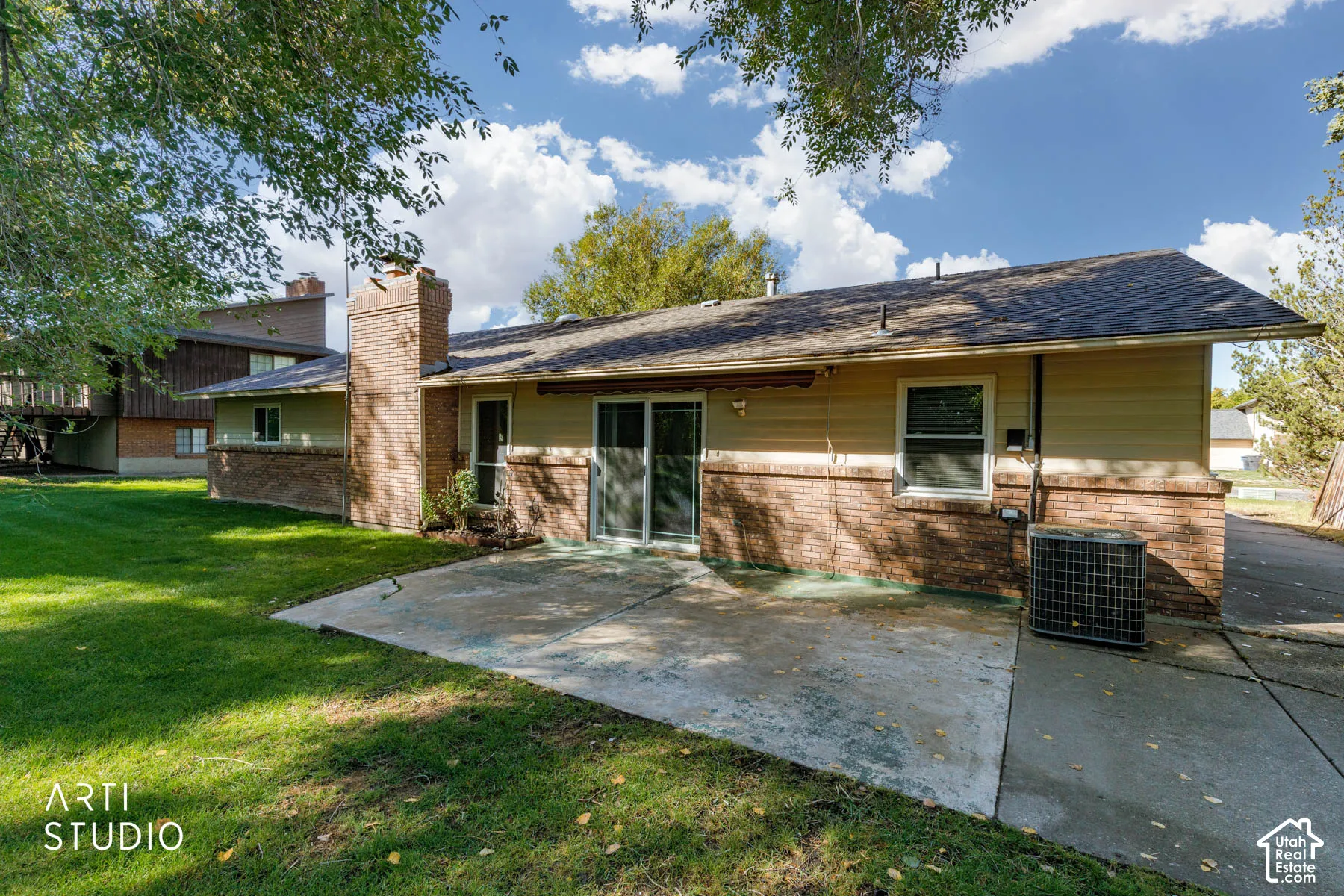 Expansive concrete patio with brick and siding exterior, a prominent brick chimney, and a sliding glass door