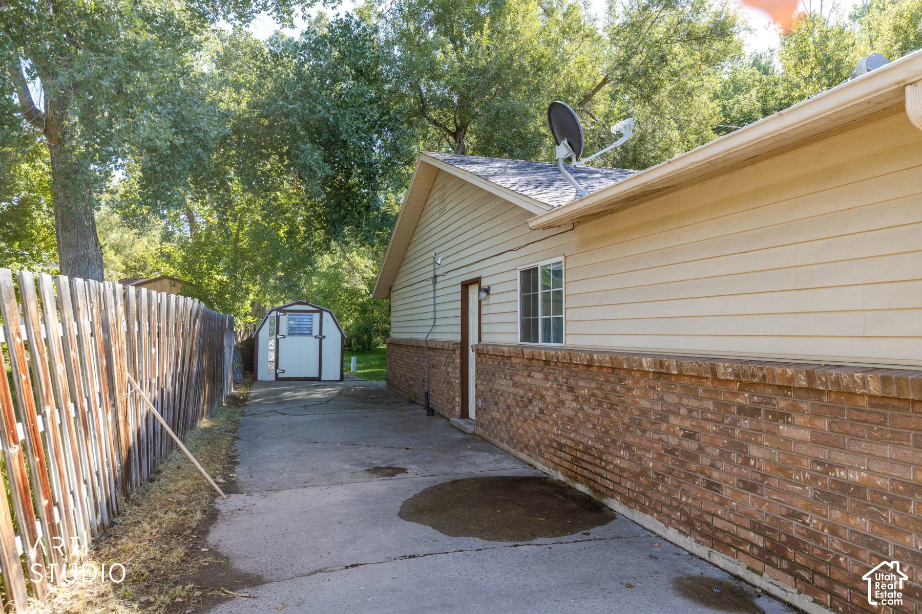 Brick and siding exterior with a window, asphalt driveway, and a storage shed
