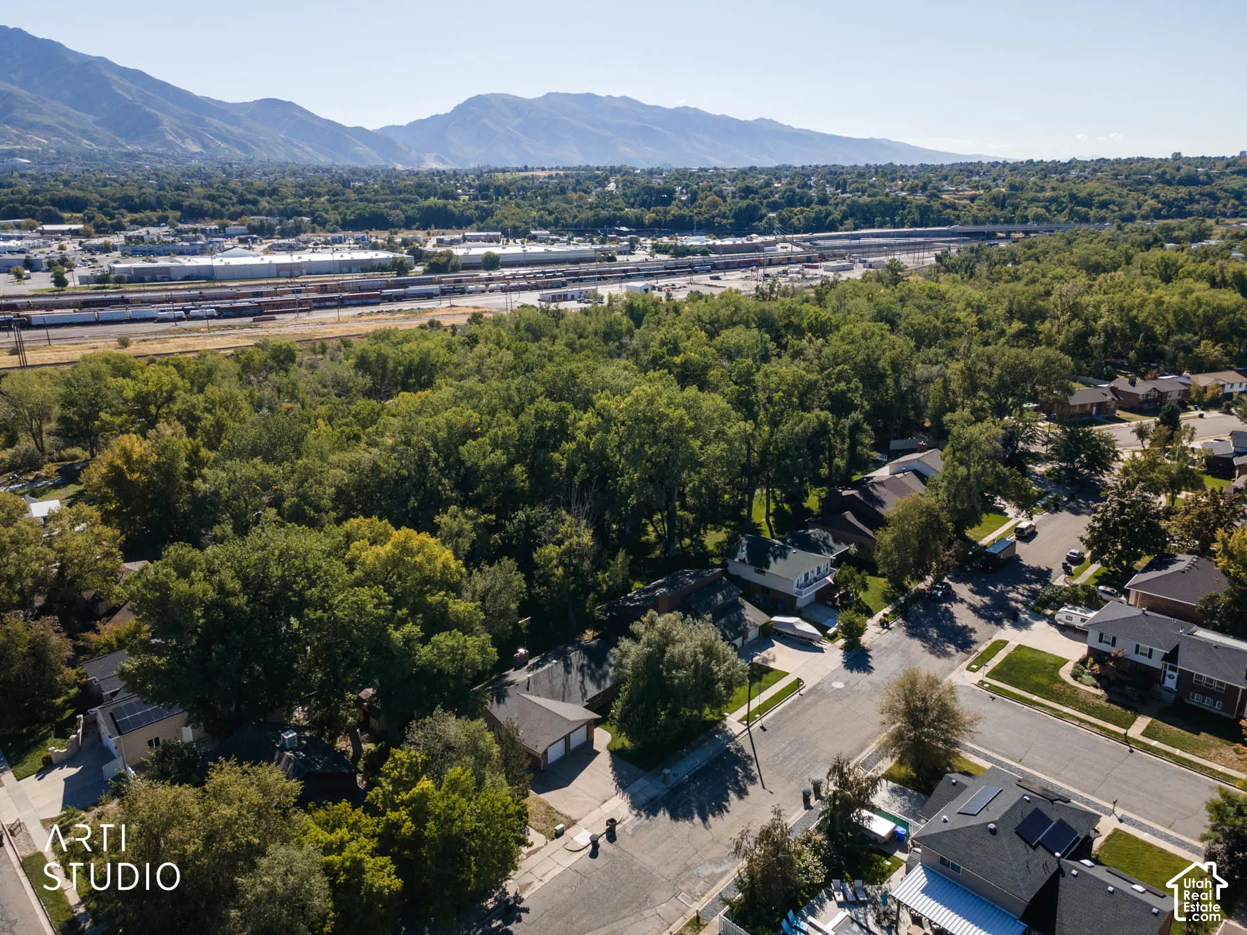 Mountain backdrop, mature trees, residential neighborhood, nearby rail lines, solar panels visible on a rooftop