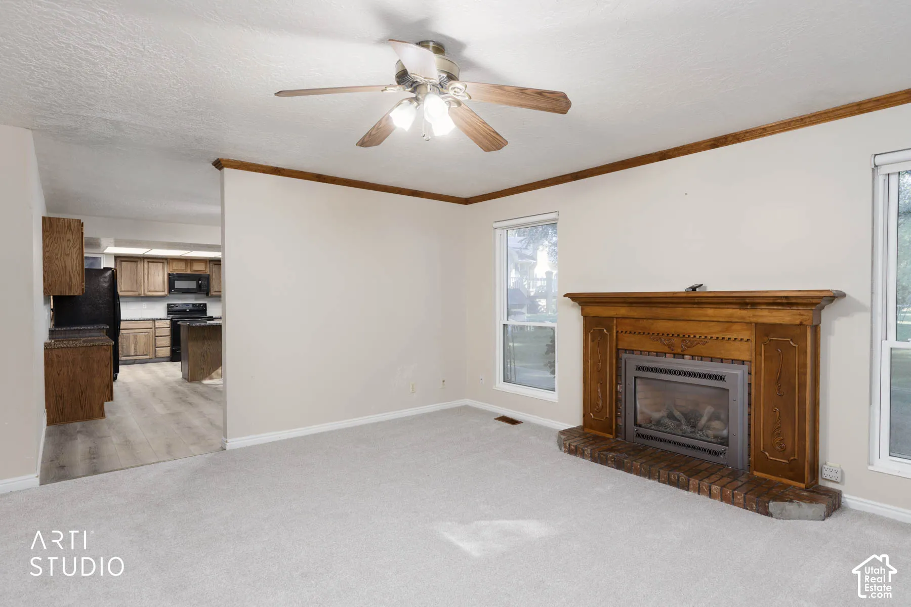 Living area featuring a ceiling fan, wood-finish mantel, brick fireplace surround, and carpet flooring