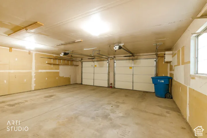 Two overhead garage doors with automatic openers, concrete flooring, and an exterior window