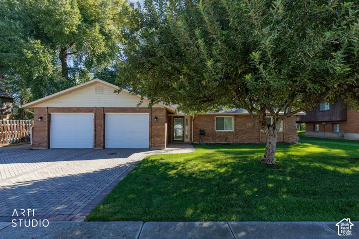 Brick exterior with a gabled roofline, two-car garage, paved driveway, and established front yard landscaping