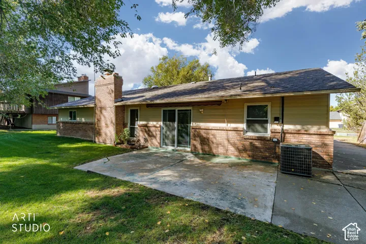 Expansive concrete patio with brick and siding exterior, a prominent brick chimney, and a sliding glass door