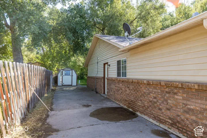 Brick and siding exterior with a window, asphalt driveway, and a storage shed