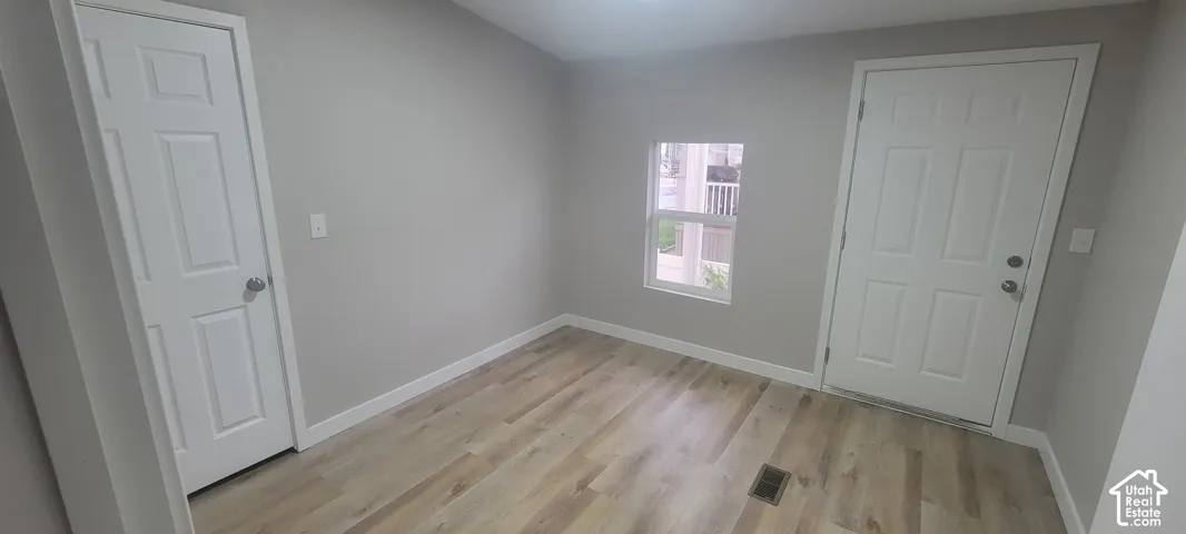 Wood-finish flooring with light-toned walls, white trim, and a paneled door