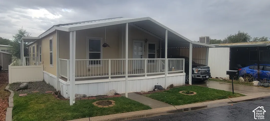 Front exterior with a covered porch, white railing, and an extended covered carport