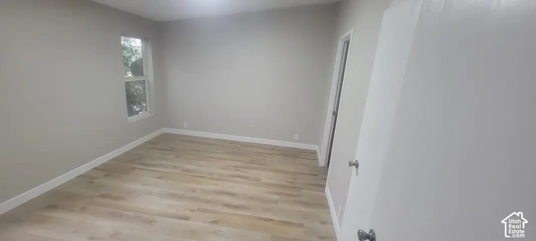 Light-toned wood-finish flooring, neutral wall tones, and a window with white trim