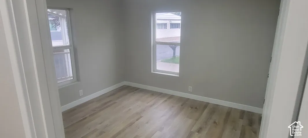 Wood-finish flooring with crisp white trim, neutral wall paint, and two windows providing natural light