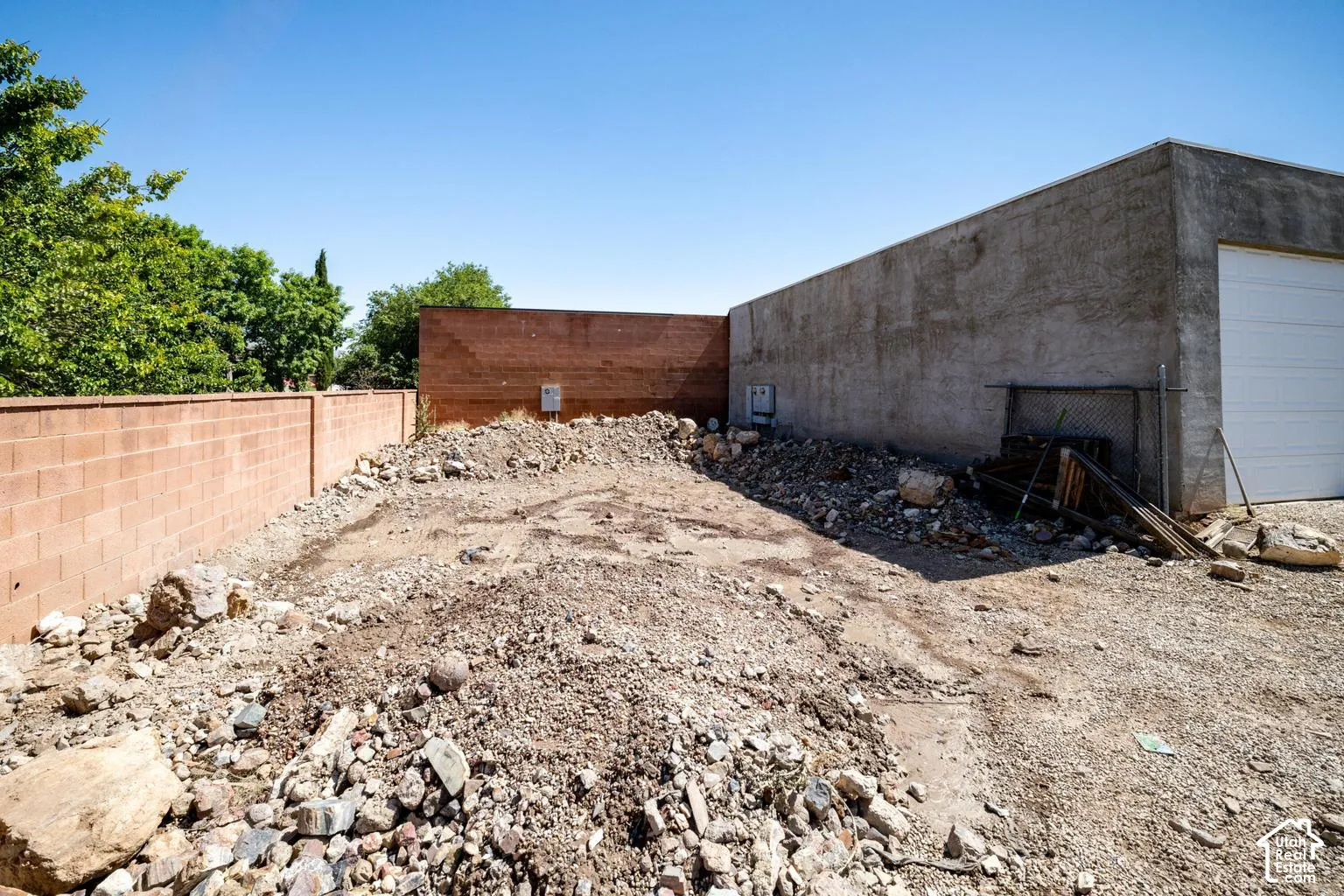 Masonry block wall, stucco-finished building, and a white roll-up door