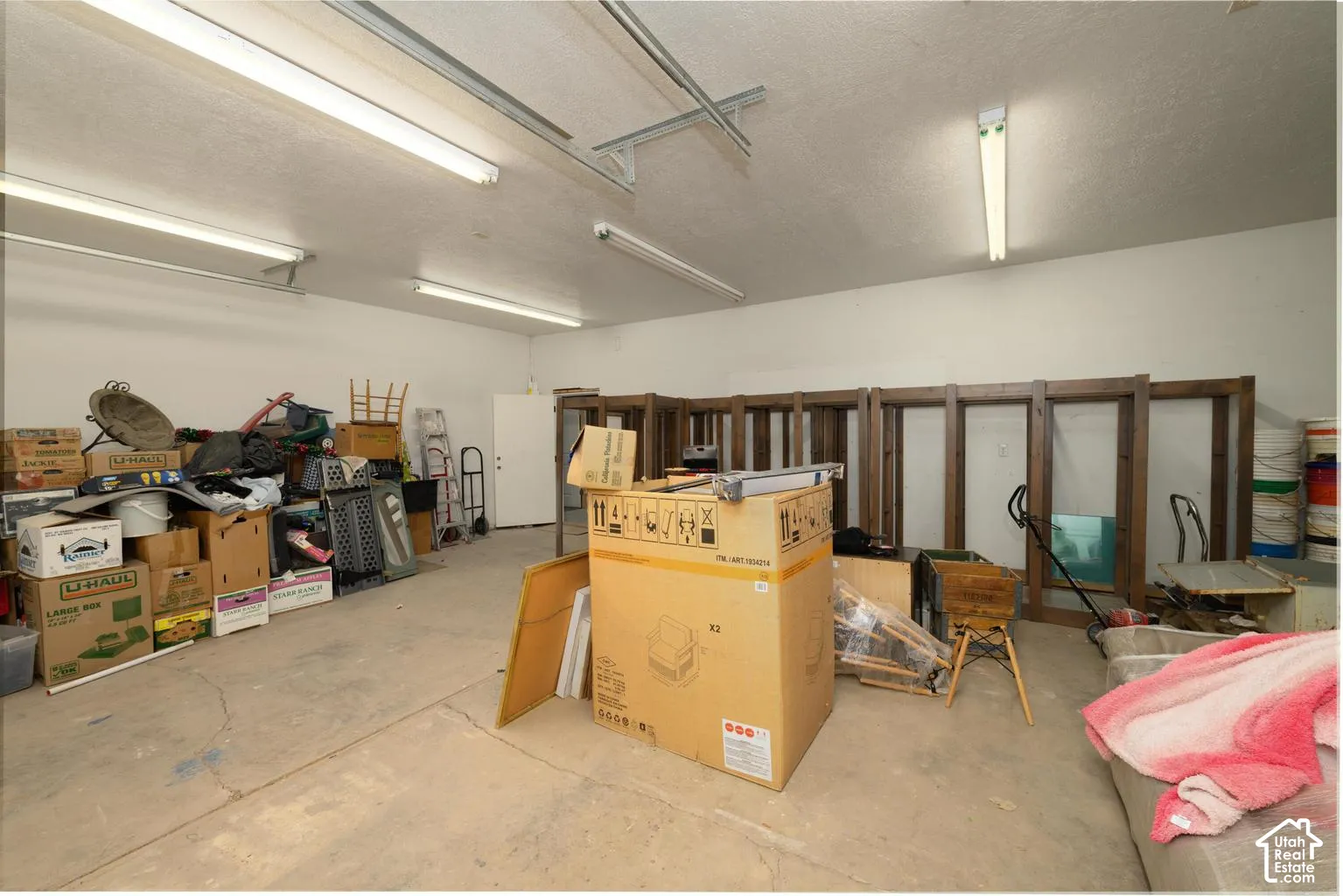 Concrete flooring, white painted walls, and fluorescent overhead lighting
