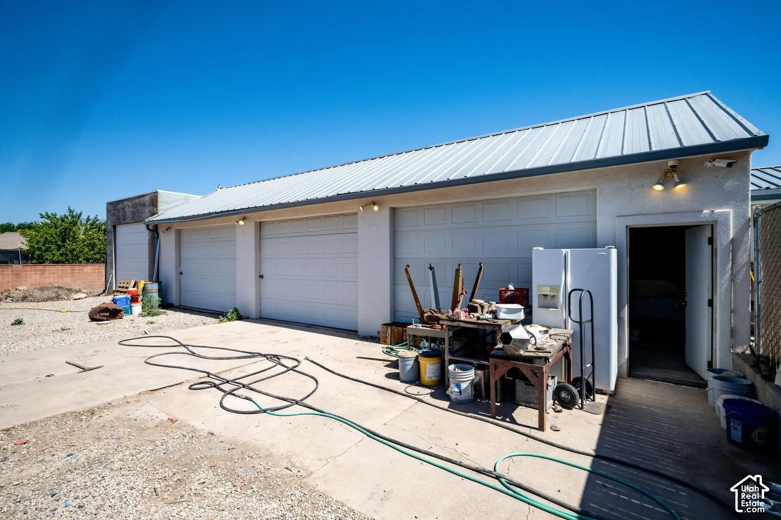 Detached structure with multiple garage doors, a metal roof, and exterior lighting