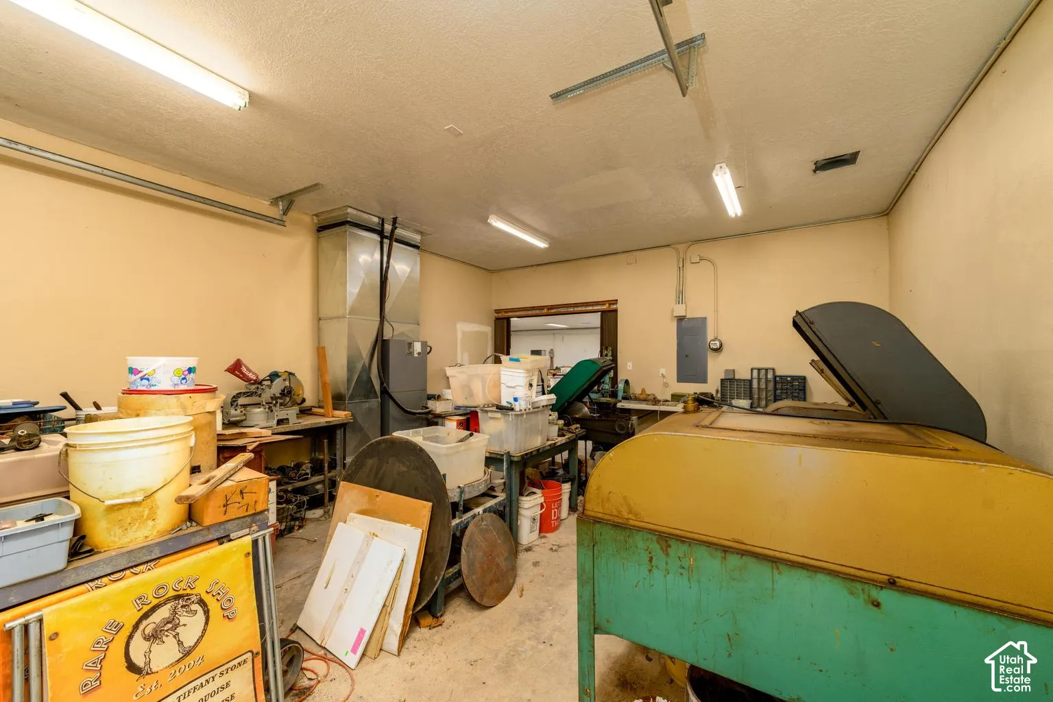 Large workshop area with exposed ductwork, fluorescent lighting, and a neutral wall finish