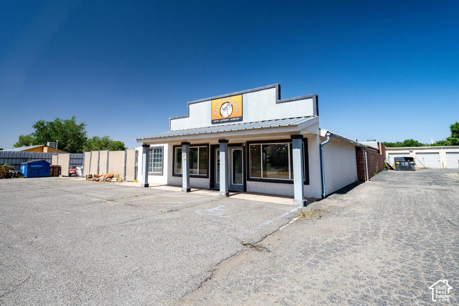 Single-story commercial building featuring a prominent storefront, multiple large windows, a covered entrance, and a metal roof