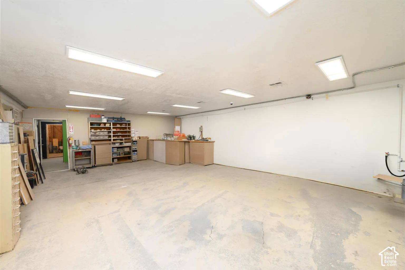 Expansive open room featuring concrete flooring, fluorescent lighting, and a white ceiling