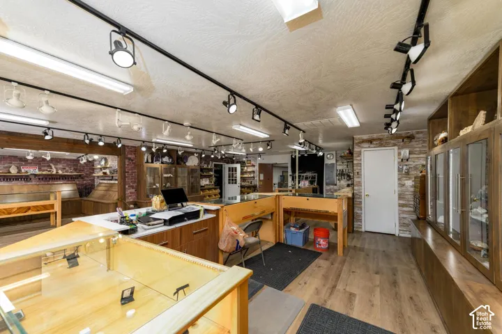 Wood-finish flooring, track lighting, exposed brick wall, white paneled door, and built-in display cabinetry