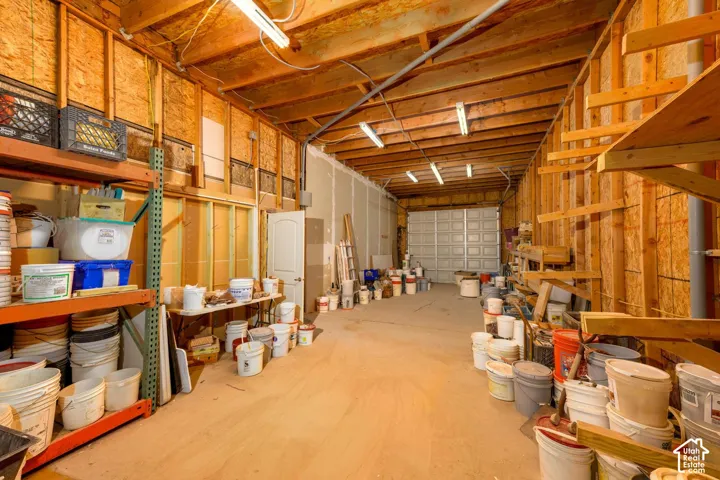 Exposed wood beam ceiling, fluorescent lighting, and unfinished wood stud walls