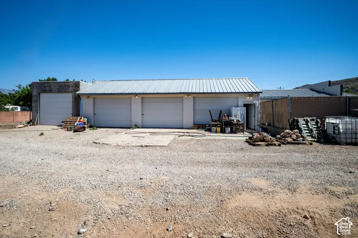 Building with multiple garage doors, metal roof, and concrete foundation