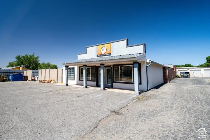 Single-story commercial building featuring a prominent storefront, multiple large windows, a covered entrance, and a metal roof