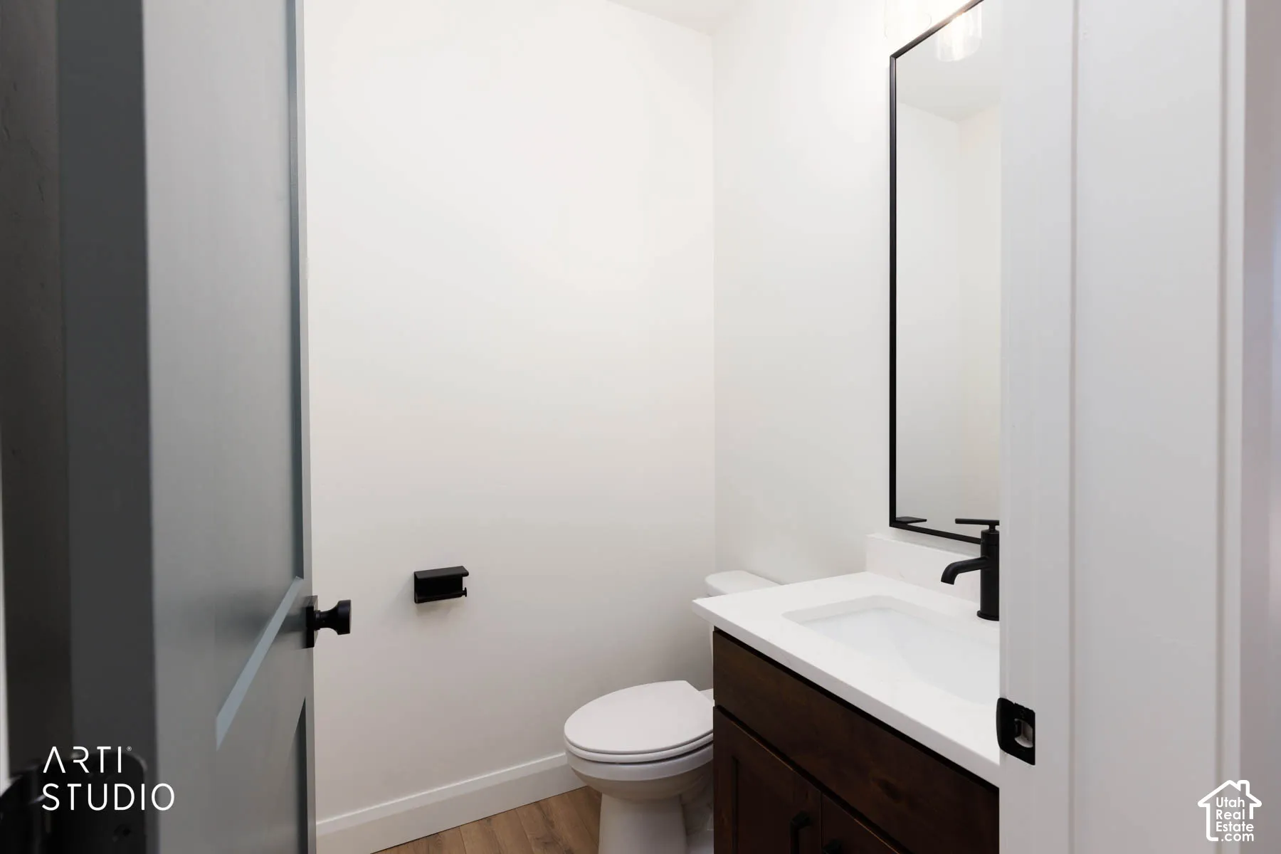 Vanity with a white countertop and integrated sink, matte black faucet, and dark wood-finish cabinetry in the half bath