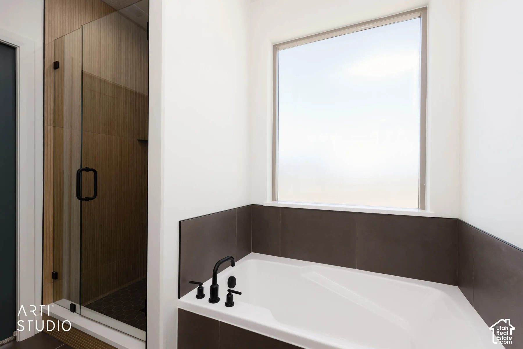 Built-in soaking tub with matte black fixtures, set against a tiled surround