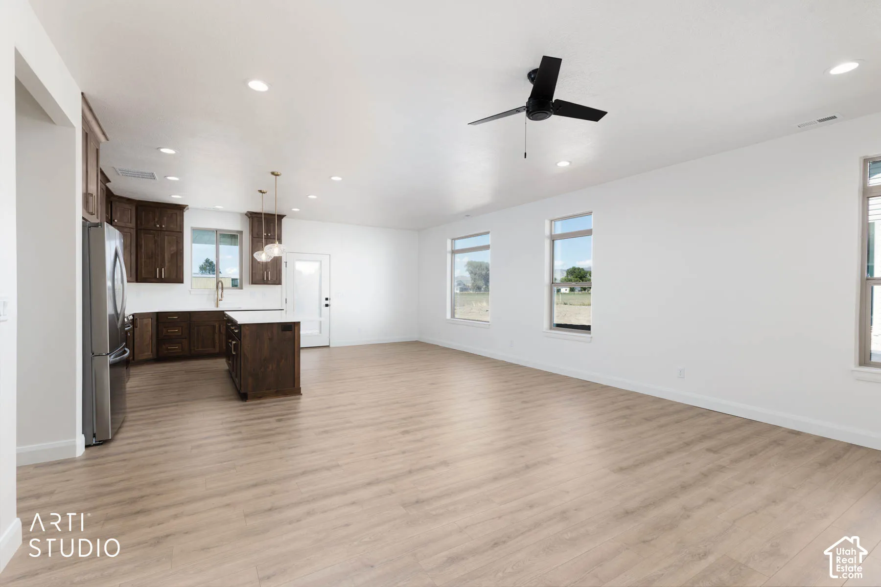 Open-concept living space with wood-finish flooring, recessed lighting, and a black ceiling fan.