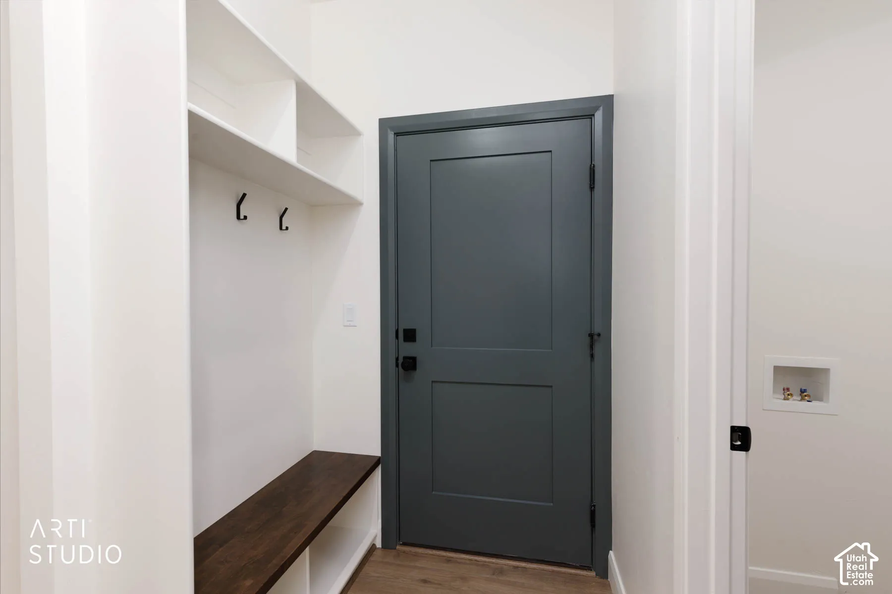 Built-in bench with wood-finish top, white shelving, and black coat hooks