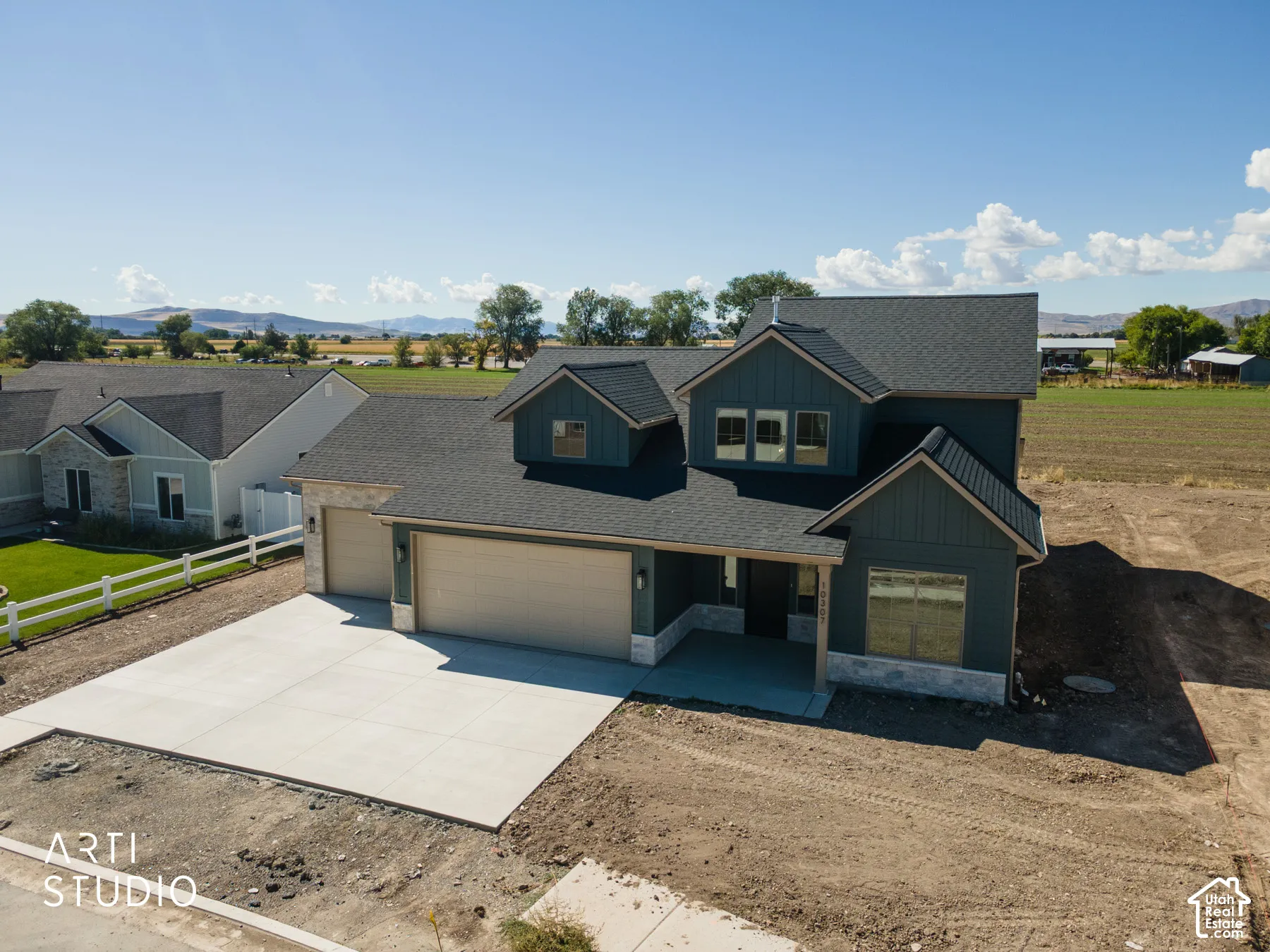 Two-story exterior with dark siding and stone accents, concrete driveway, and attached two-car garage