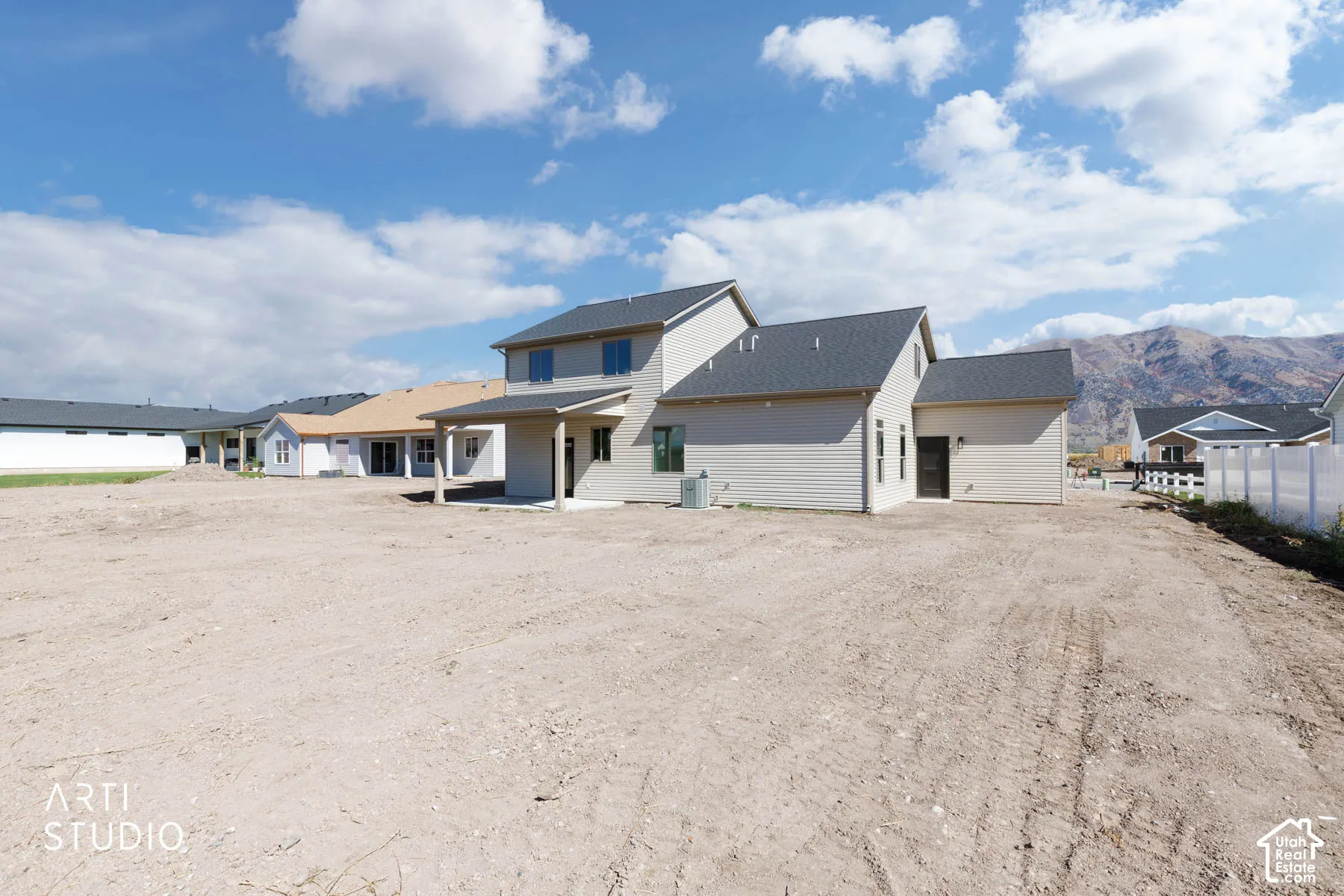 Two-story residence with light-toned siding, dark shingled roofing, and a covered back patio