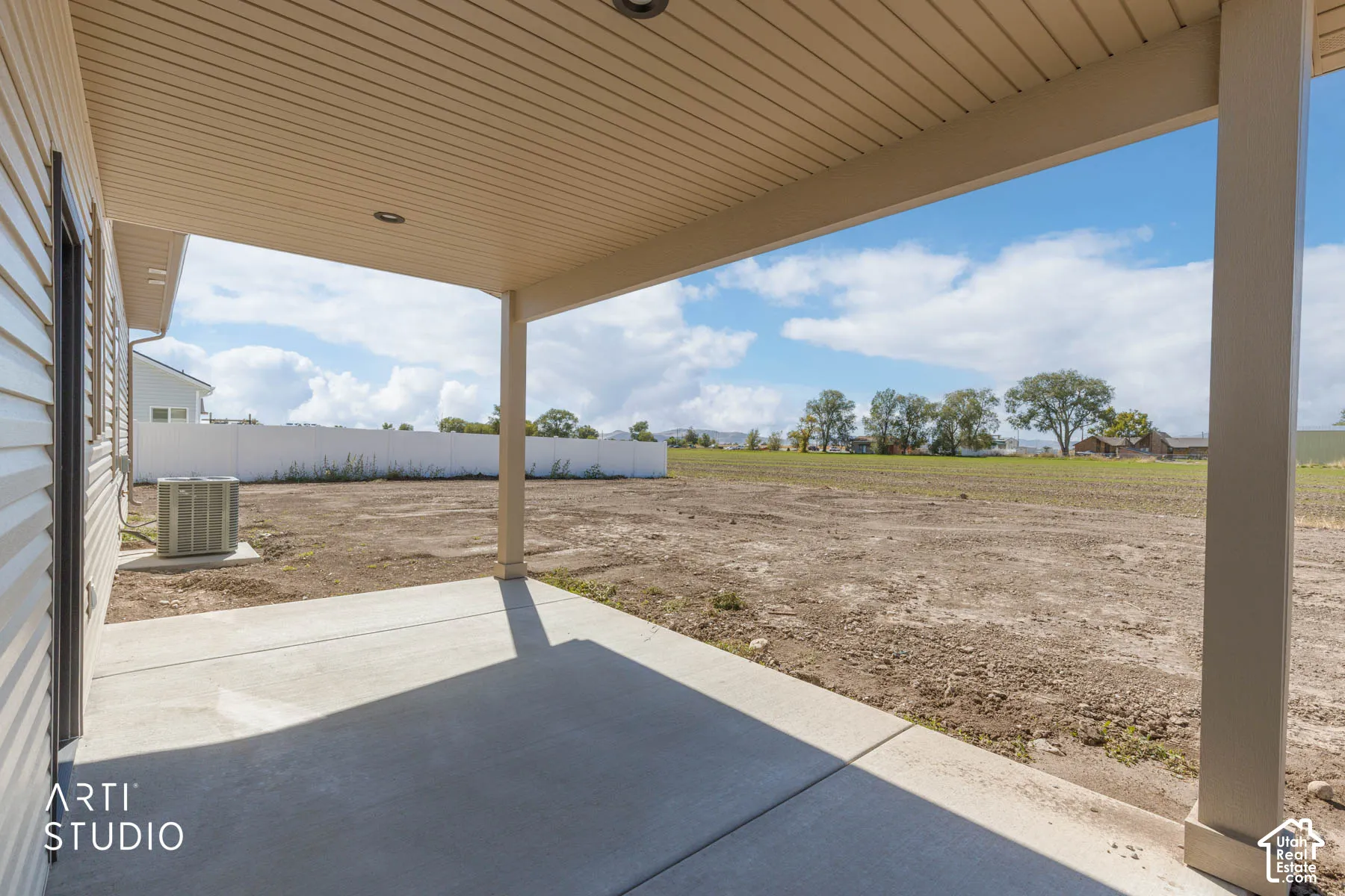 Covered concrete patio with recessed lighting, beige soffit, and a spacious yard area